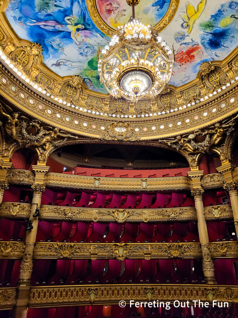 Palais Garnier, the stunning Paris Opera House. A 7-ton chandelier hangs from a ceiling painted by Marc Chagall over red velvet seats.