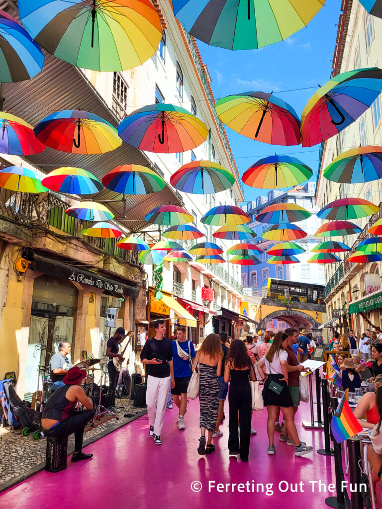 Pink street with rainbow umbrellas in Lisbon Portugal