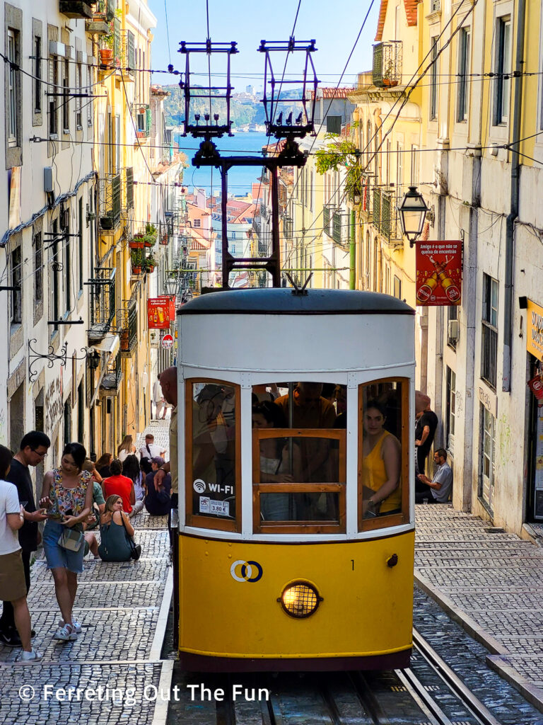 An iconic yellow tram climbs a hill in Lisbon Portugal