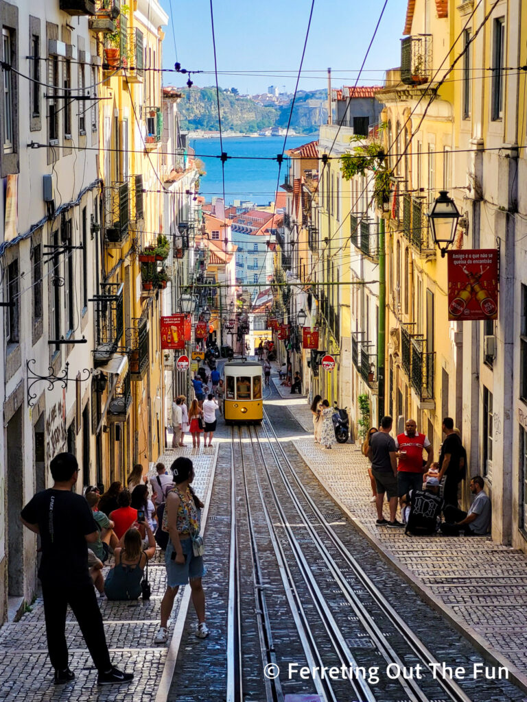 A yellow tram climbing a steep hill in Lisbon Portugal