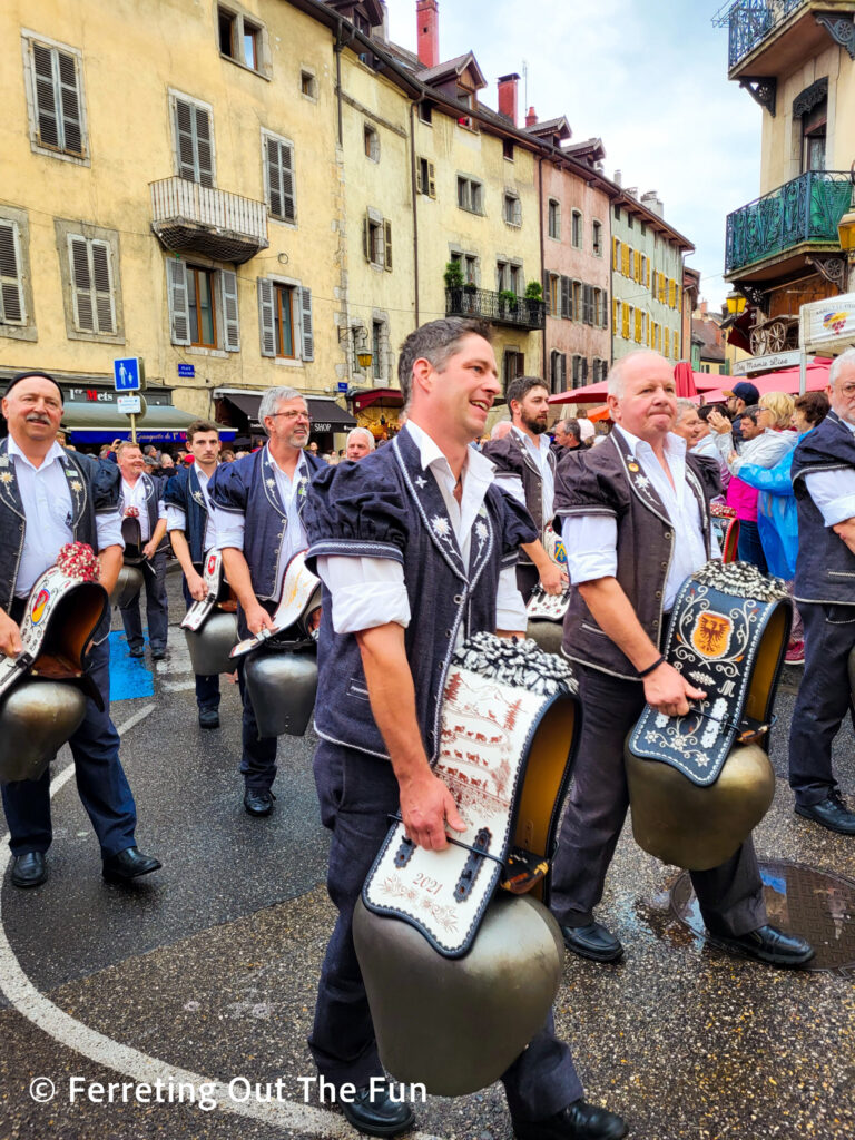 Men in traditional costumes carry giant cowbells in the parade celebrating the cows' return from the Alpine pastures in Annecy France